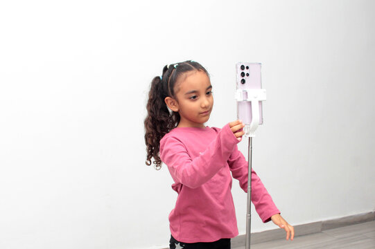 6-year-old Latina girl with dark hair and curls records videos for social media, dancing and telling storytime