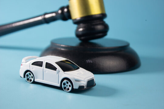 miniature car and legal gavel, symbolizing hit-and-run accidents, illegal street racing, traffic violations, reckless driving, road safety laws, criminal liability, and legal consequences of dangerous