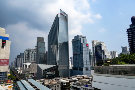 Modern Bangkok skyline with the distinctive UOB building, nearby office towers and elevated railway tracks beneath clouds, Thailand, Bangkok, April 26, 2026.
