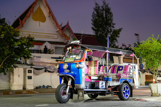 Colorfully decorated Thai tuk tuk taxi stands at night in front of a traditional building illuminated by streetlights in Bangkok, Thailand, Bangkok, April 26, 2026.