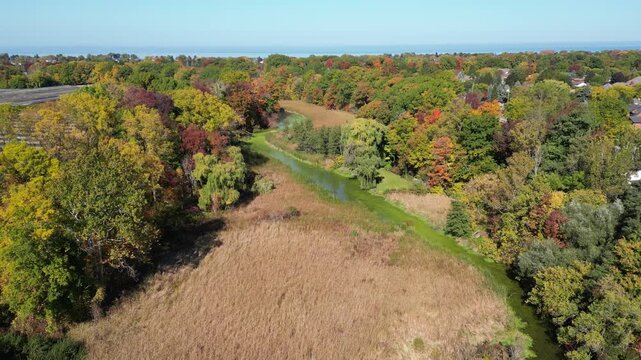 Aerial moving forward over Richardson's Creek towards Lake Ontario near Martindale Road in north St. Catharines, Ontario, Canada on a sunny Autumn day in October, 2024.