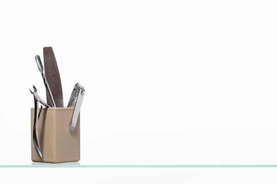 Minimalist arrangement of essential nail care products including various grit emery boards, files, and wooden orange sticks in a stylish leather container, perfect for beauty salon branding.