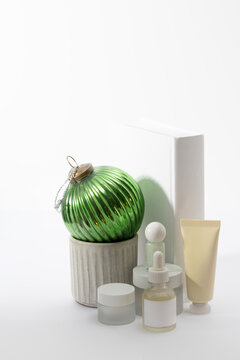 Festive skincare gift set with a green glass ornament, cream tube, and serum bottle. Ideal for natural beauty holiday sales, Christmas morning presents, and winter wellness promotional campaigns.
