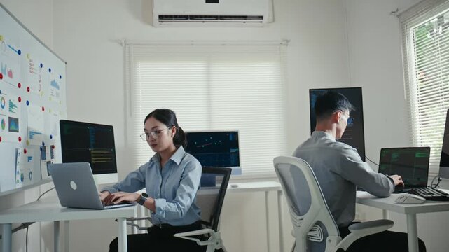 Asian computer programmers coding in a modern startup office
