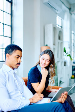 Diverse business colleagues reviewing data on a tablet, working together in a modern startup office environment