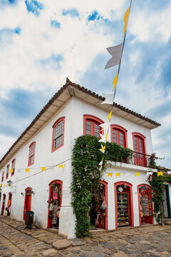 Historic White Colonial Building with Red Trim and Green Vines on Cobblestone Street in Paraty Brazil