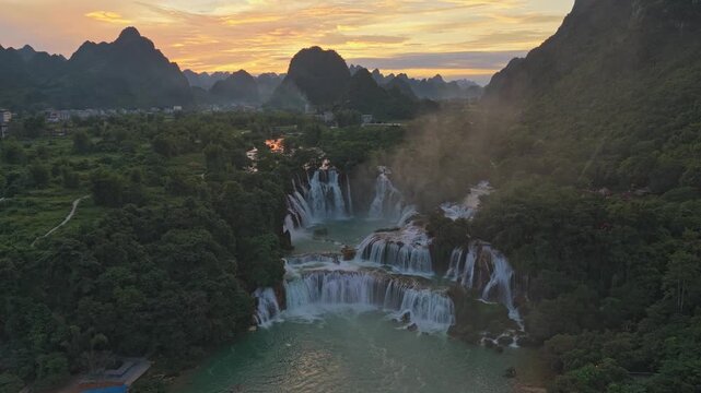 Stunning aerial perspective of the magnificent ban gioc detian falls, showcasing the powerful cascades surrounded by lush green mountains at sunset