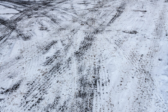 Vehicle Tire Tracks Mark a Muddy Snow Covered Road