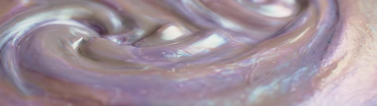 Pearlescent surface showing swirling nacreous material with a glossy sheen and gentle undulations reflecting soft light.
