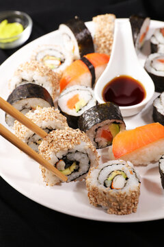 Eating sushi with chopsticks from plate with soy sauce and wasabi