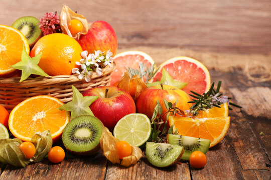Assorted fresh tropical fruits with citrus and kiwi in basket on rustic wood