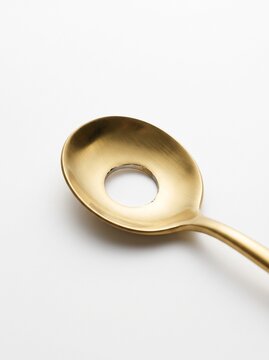 Golden metal spoon with a large hole in the middle, uselessness, inefficiency and false promise business concept.