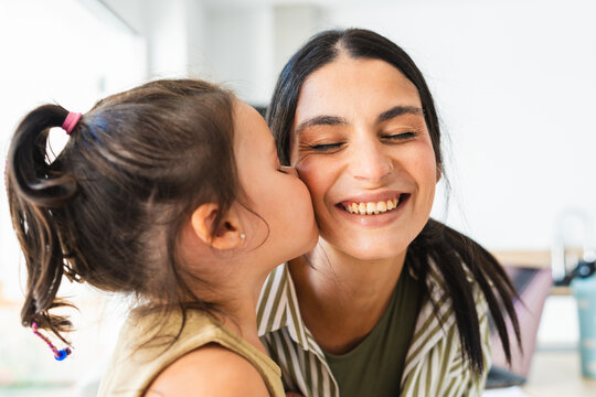 Daughter kisses her smiling mother at home