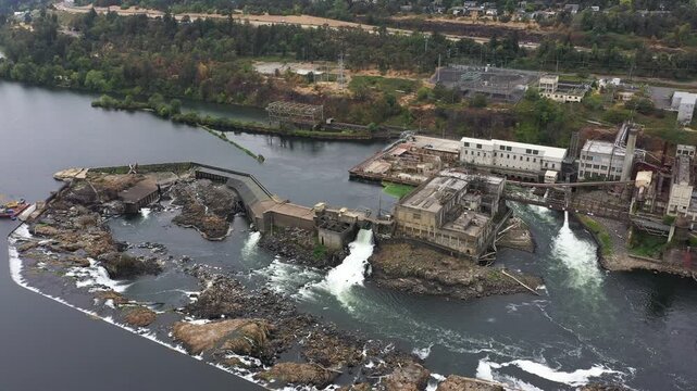 4K aerial drone footage of Willamette Falls near Portland, Oregon, USA, showing historical hydroelectric power plant, paper mill buildings, waterfalls, Willamette River and industrial infrastructure
