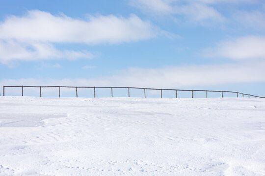 A long row of wooden posts are in the snow