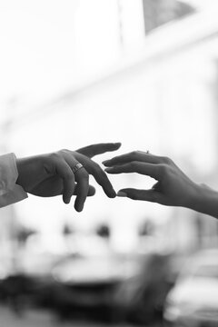 Black and white couple reaching hands touching wedding rings