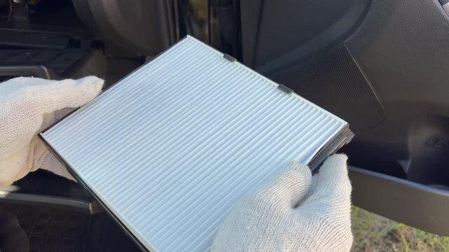 A mechanic holds a new, clean car cabin filter during maintenance. Vehicle maintenance