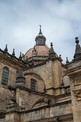 Architectural detail of the Cathedral of Jerez de la Frontera in Andalusia, Spain, featuring the cathedral dome, flying buttresses, pinnacles and ornate stonework beneath a cloudy sky. © ihervas