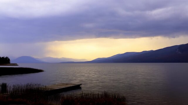 Stormy mountain lake with drifting clouds, falling rain. Nature documentaries, weather programming, and travel promotion.