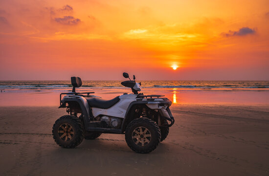 Quad bike At twilight sky sunset on the tropical beach. ATV quad tracks on the golden beach sand