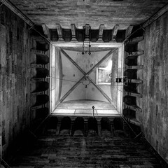 Black and white upward perspective view inside the historic Giotto's Campanile (bell tower) in Florence, showing geometric stone architecture and vaulted ceiling © Yu