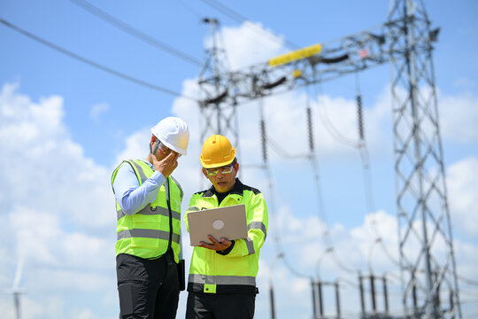 Electrical engineer and technician inspecting power substation equipment with tablet