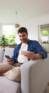 Man holding up a blank card with a smartphone in his other hand
