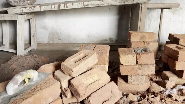 Red clay bricks stacked inside unfinished building under construction with wooden workbench and concrete materials video
