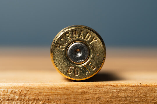 BALTIC STATES - OCTOBER 12, 2026: Macro shot of the headstamp on a Hornady .50 Action Express (50 AE) bullet casing standing on a wooden surface against a gray background.
