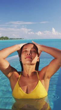 Sexy Asian bikini model woman coming out of water in infinity pool at luxury hotel resort in slow motion Swimsuit body summer vacation travel tan. Raw video of real woman model without any makeup