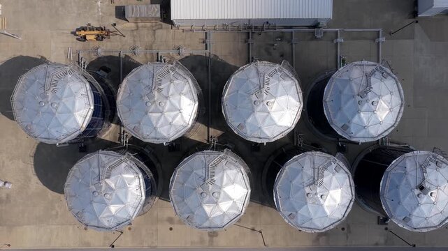 Massive chilled water thermal storage tanks and complex cooling infrastructure in an industrial facility - rising aerial reveal