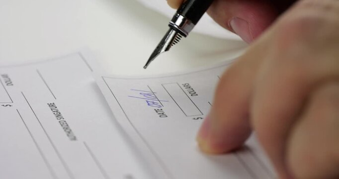 Hand writes on form with black pen. Person completes paperwork and signs document at desk. Close-up shows business administration, application process, office documentation, and work.