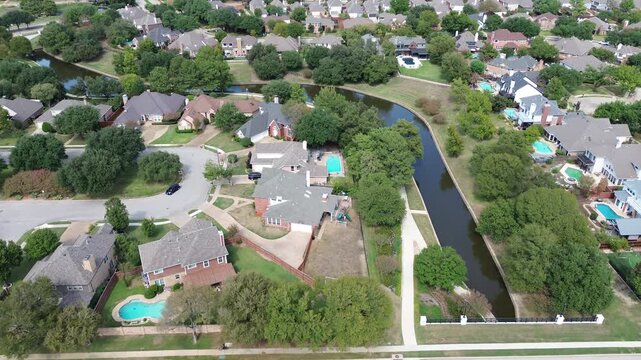 Curving canals slice across properties, exposing backyard pools along Valley Ranch Corridor. Emerald lawns flank concrete walkways, displaying meticulous landscaping. . USA, Irving, Texas