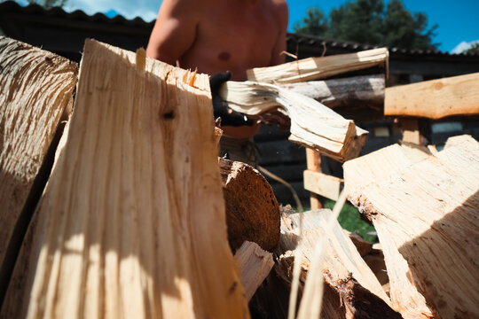 Man loading split firewood into wheelbarrow for winter heating preparation and country house yard work concept