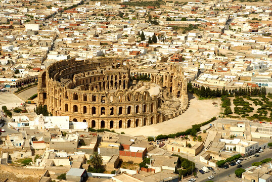 Stunning elevated panoramic view of the majestic Roman amphitheater of El Jem (Thysdrus) surrounded by the modern white buildings of the city. A famous UNESCO World Heritage site in Tunisia.