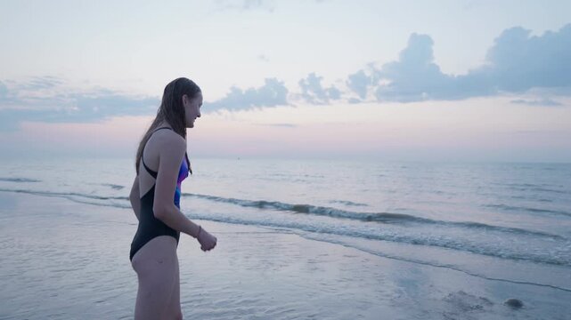 The girl is afraid of jellyfish and throws sand at the beach wet hair camera movement around