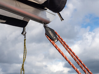 Close-Up Of Sailboat Rigging With Block Pulley And Red Control Lines Against Cloudy Sky © Michał Kiełbicki