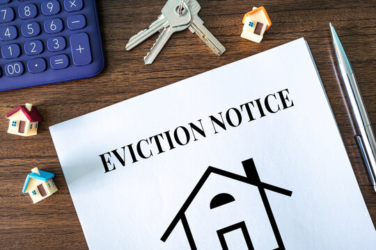 Eviction Notice document with keys toy houses and calculator on wooden desk, real estate and tenant law concept