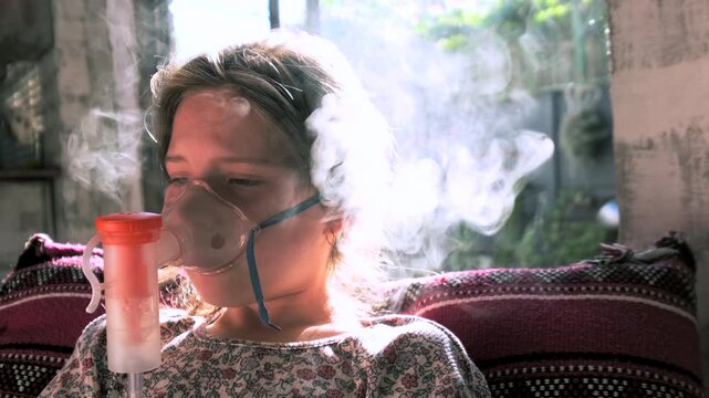 Young girl uncomfortable using nebulizer and inhaling fine mist for bronchitis