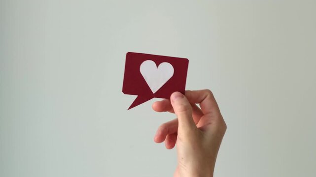 Social media and digital communication concept video featuring a hand holding a red speech bubble icon with a white heart symbol.