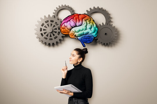 Businesswoman with notebook beneath colorful brain and gears, symbolizing education, brainstorming, learning, intelligence, and creative thinking.