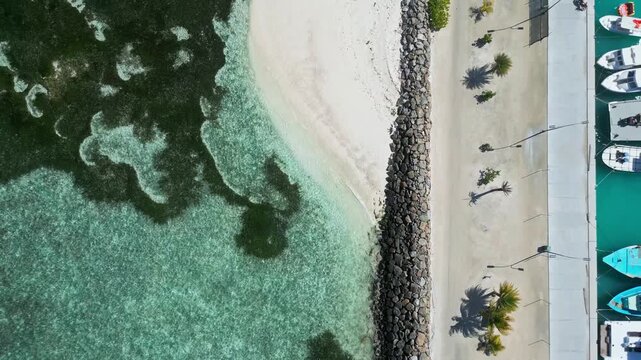 Overhead drone shot of stone breakwater, sandy beach, and clear turquoise lagoon with dark coral reef. Great backdrop scene for coastal construction and travel media.Himmafushi.Maldives