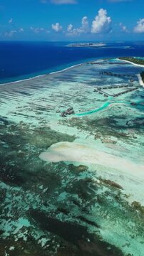 Aerial establishing view of luxury tropical resort islands in crystal clear ocean water. Ideal backdrop for honeymoon promo, relax video, summer getaway, and spa concept, vertical video