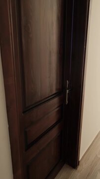 Depressed man sitting on his bed with head lowered turns toward the doorway and closes the door, choosing isolation from daylight and retreating from the outside world in a dark bedroom Vertical