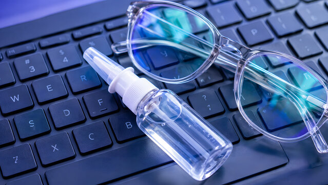 Blue Computer Keyboard with Reading Glasses and Eyedropper for Digital Eye Strain Concept