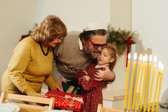 Grandparents celebrating hanukkah with granddaughter receiving gifts