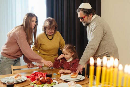 Jewish family celebrating hanukkah playing dreidel together