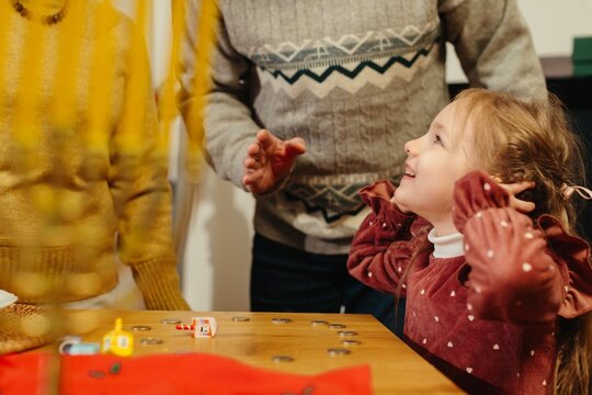 Girl celebrating hanukkah playing dreidel game with family