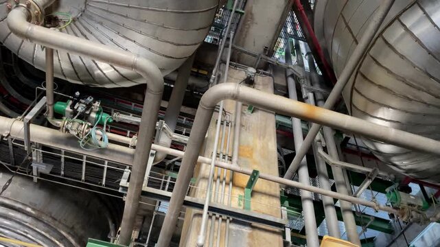 Industrial oil processing facility showing complex pipe arrangements, mechanical valves and structural steel engineering.