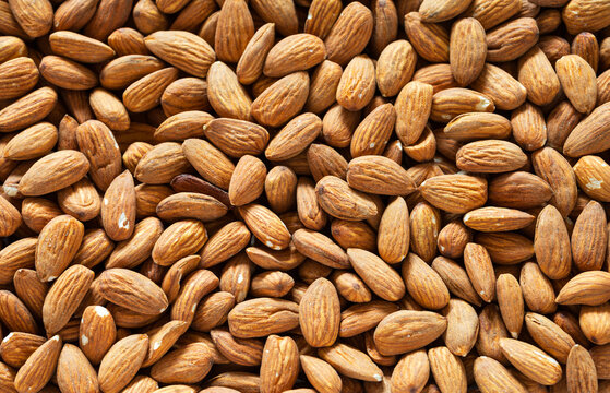 Edible background of shelled almonds. Oval edible nutlike seeds or kernels. Organic, healthy vegetarian food. Close-up, top view, flat lay, creative mock up